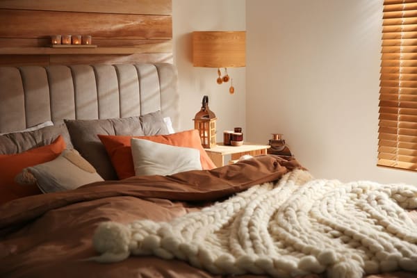 ein gemütliches Schlafzimmer-Interieur mit orangen Farben und warmen Textilien, einschließlich einer gestrickten Decke